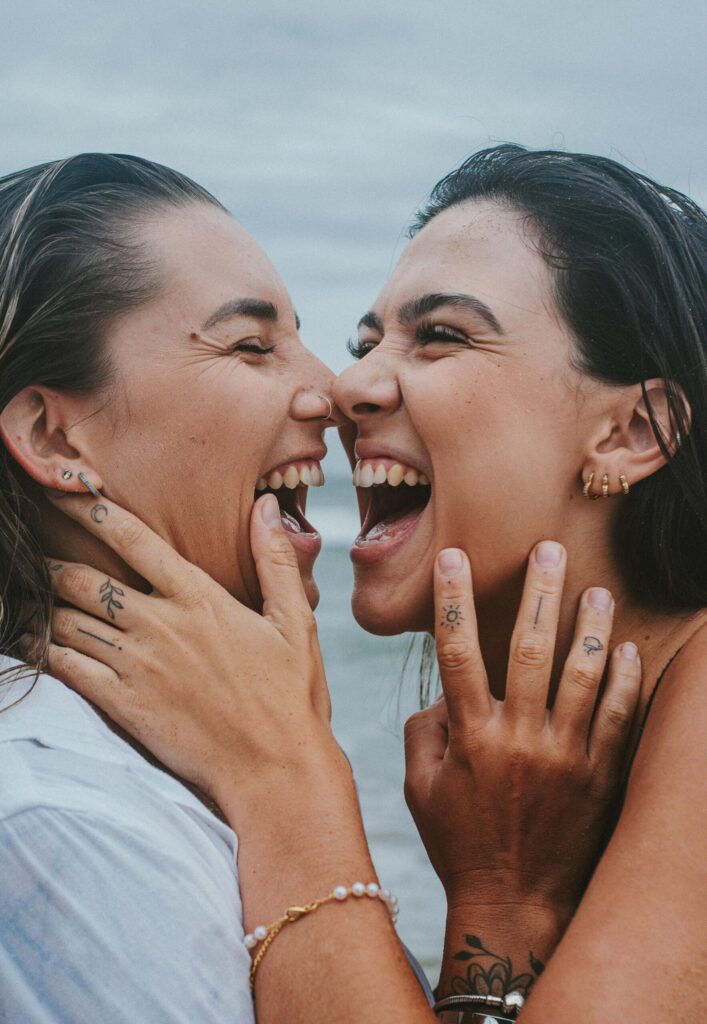 Two happy women expressing joy and love by the sea, showcasing LGBTQ pride.