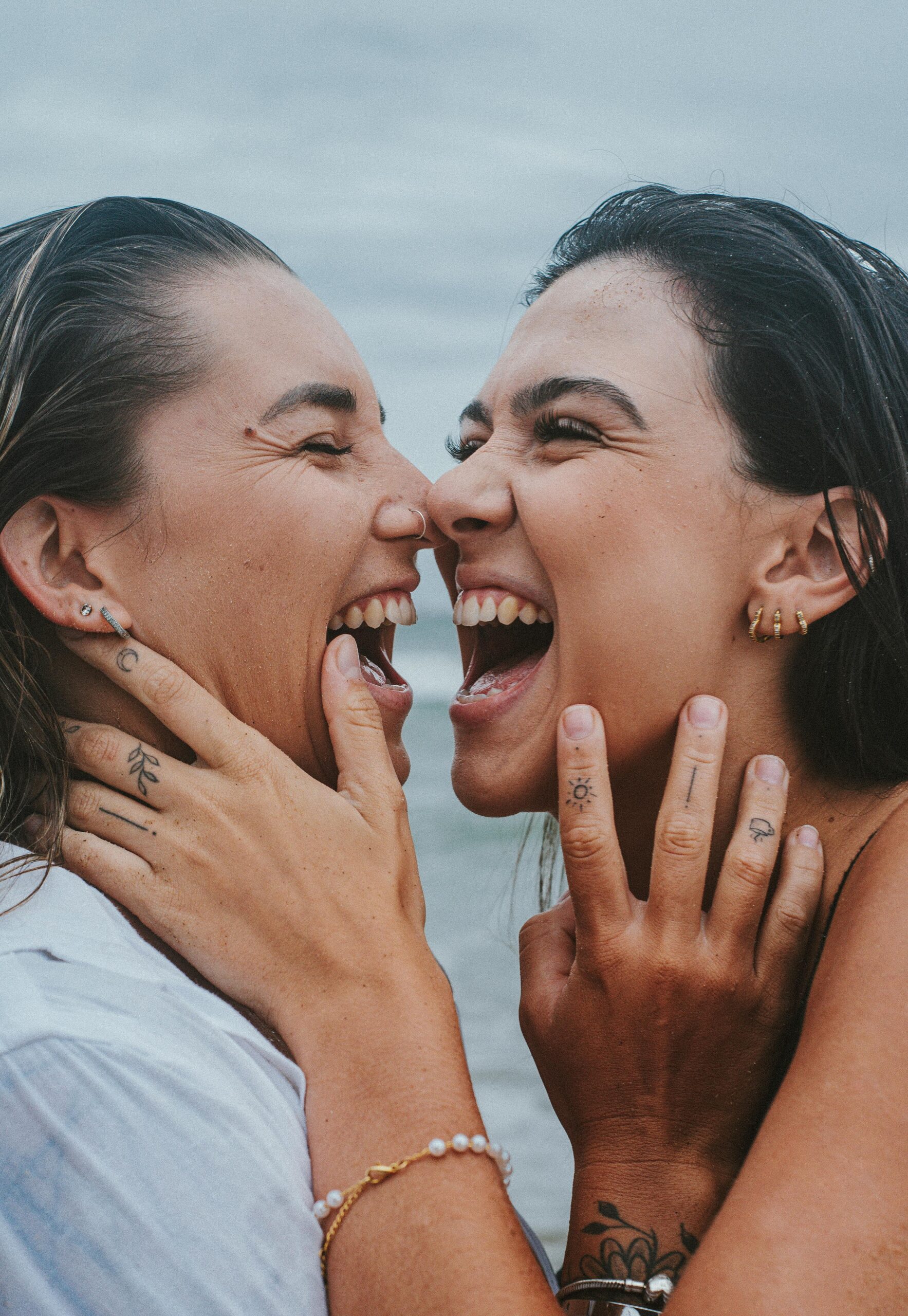 Two happy women expressing joy and love by the sea, showcasing LGBTQ pride.